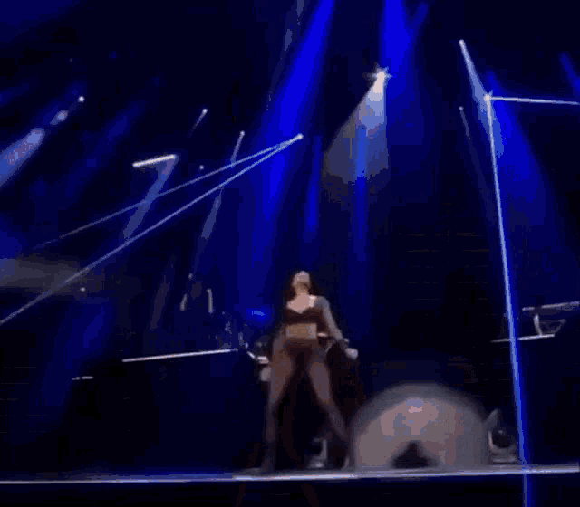 a woman in a black bra and tights is dancing on stage .