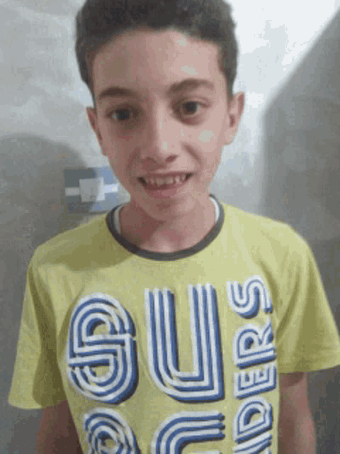 a young boy is wearing a yellow shirt that says supers on it