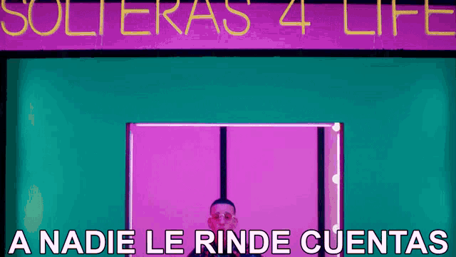 a man is standing in front of a neon sign that says solteras 4 life