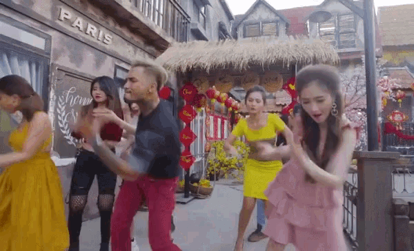 a group of people are dancing in front of a building that has the word paris on it
