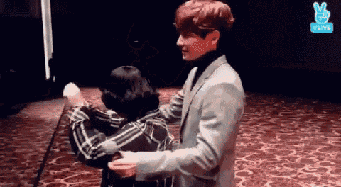 a man in a suit is hugging a woman in a plaid shirt on a red carpet .