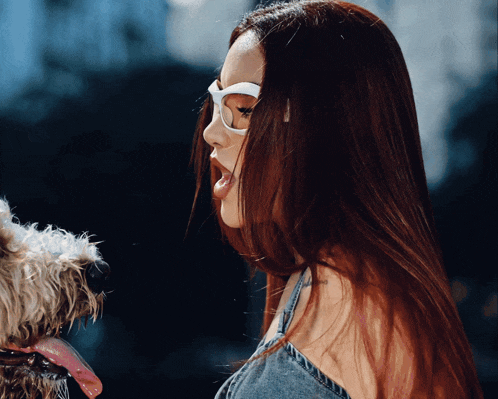 a woman wearing glasses holds a small dog in her arms