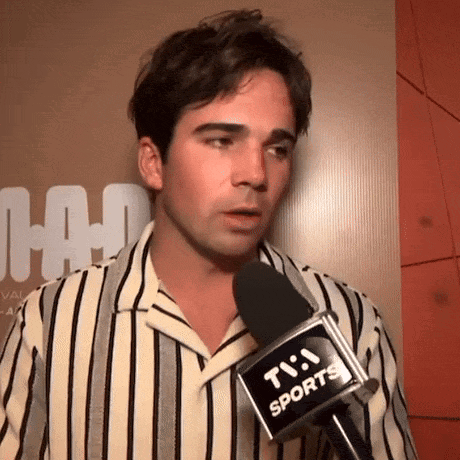 a man wearing a striped shirt is talking into a microphone .