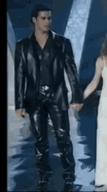 a man in a leather suit is holding a woman 's hand