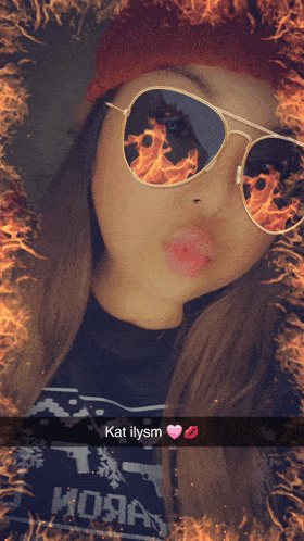 a girl wearing sunglasses with flames reflected in them says kat ilym