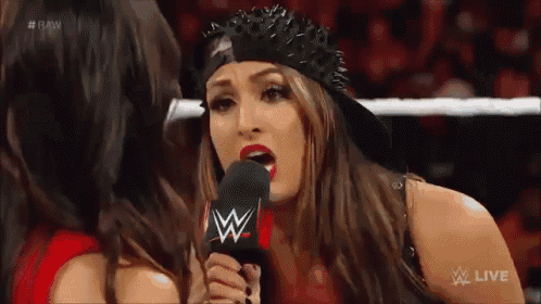 a female wrestler is talking into a microphone while wearing a black hat .