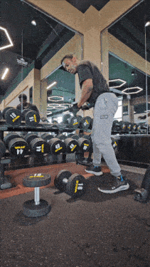 a man is lifting a dumbbell in a gym that has a row of dumbbells with the number 44 on them