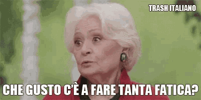 an elderly woman with white hair is wearing a red jacket and earrings and making a funny face .
