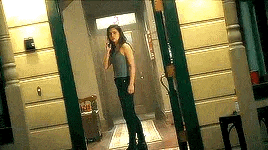 a woman is talking on a cell phone while standing in a doorway .