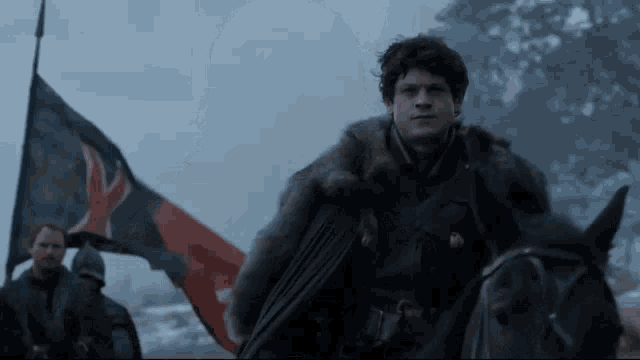 a man in a fur coat riding a horse with a flag in the background