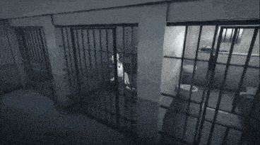 a black and white photo of a prison cell with bars