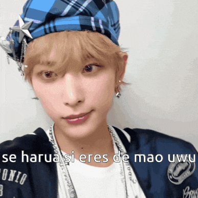 a person wearing a blue plaid hat and a bomber jacket with the words " be harua si eres de mao uwu "