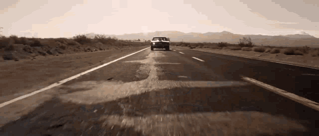 a car is driving down a highway with mountains in the background