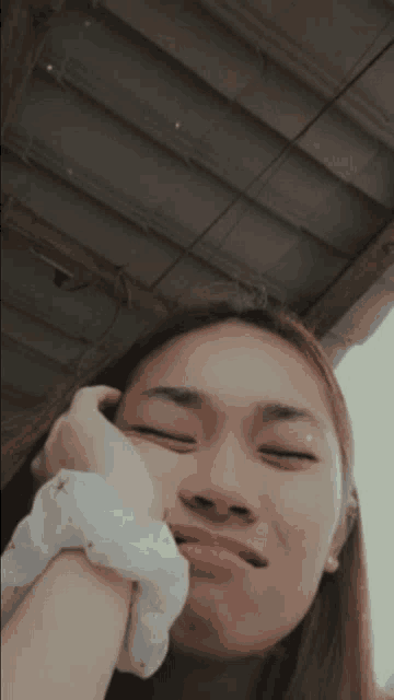 a woman wearing a white scrunchie is making a funny face with her eyes closed