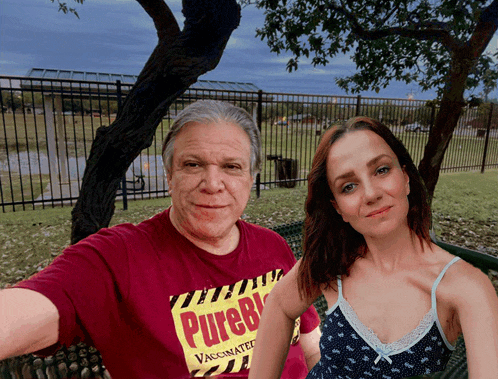 a man and a woman are sitting on a park bench and the man is wearing a shirt that says pureb