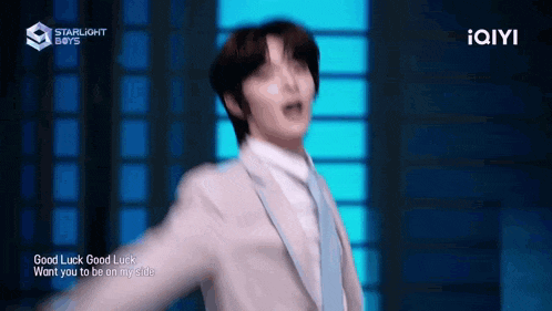 a man in a suit and tie is dancing with his arms outstretched on a stage .