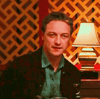 a man is sitting in front of a lamp in a room