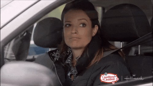 a woman is sitting in a car with a countdown to christmas sign