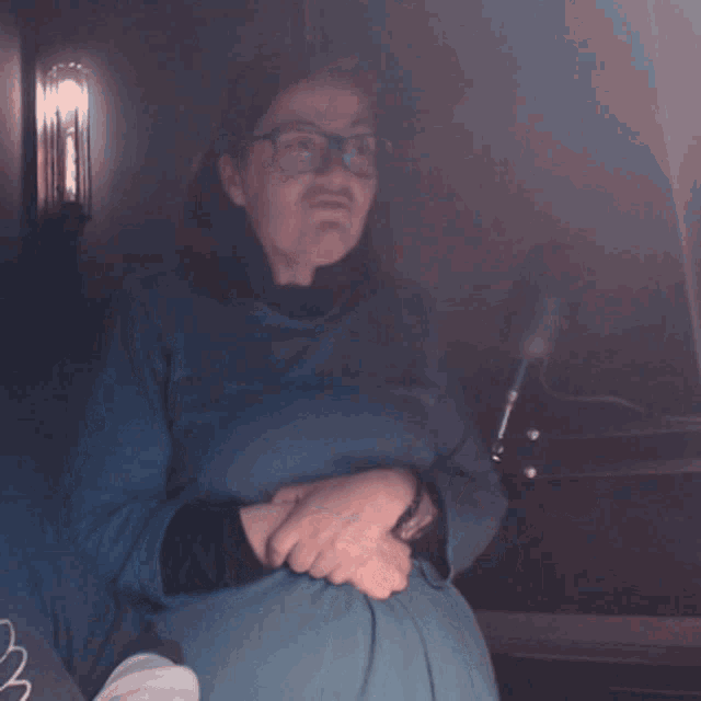 a woman in a blue shirt is talking into a microphone in a dark room