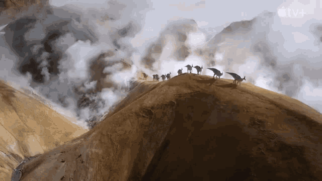 a group of animals standing on top of a mountain with the apple tv+ logo in the background