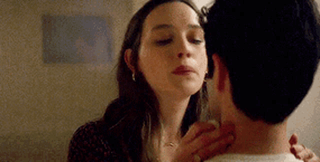 a man and a woman are kissing in a room .