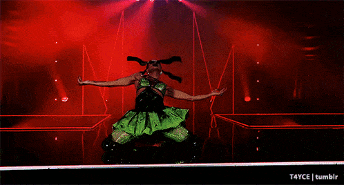 a woman in a green dress is dancing on stage
