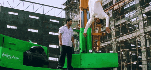 two men are standing in front of a green machine that says heavy 80 %