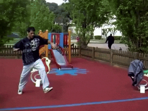 a man is doing a trick in a playground while wearing a black shirt with a tiger on it