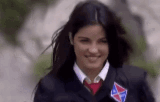 the girl is wearing a school uniform and a red tie .