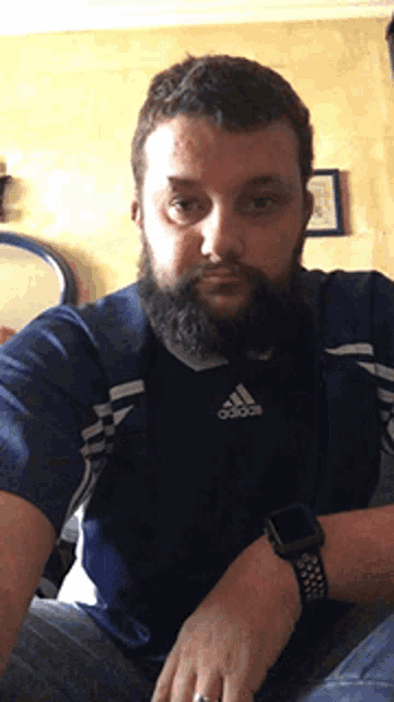 a man with a beard wears a blue adidas shirt