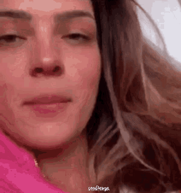 a close up of a woman 's face with a pink shirt on .