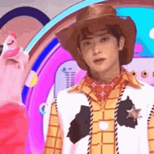 a man dressed as woody from toy story is standing in front of a pink background .