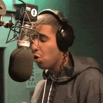a man wearing headphones is singing into a microphone with a number 1 on it