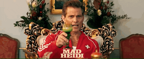 a man is sitting in a chair holding a wine glass with mad heidi written on it