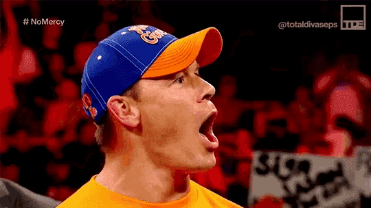 a man wearing a blue and orange baseball cap is screaming in front of a crowd .