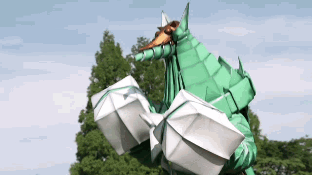 a green and white origami dragon with a long horn