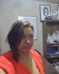 a woman in a red top is sitting on a couch in a living room