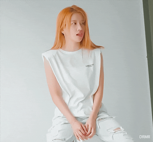 a woman wearing a white tank top that says essentials