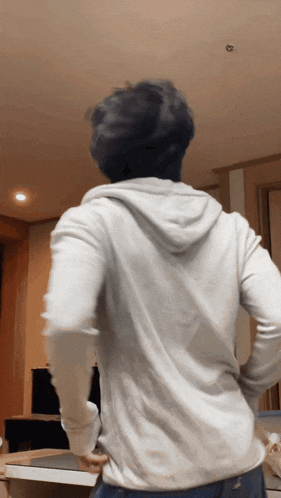 a man in a white hoodie stands in a room