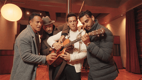 three men are playing guitars in a room and one of them has his tongue out