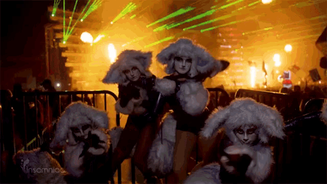 a group of women dressed in bunny costumes are standing in front of a stage with a sign that says insomniac on it