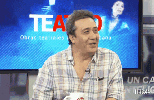 a man sitting in front of a tv screen that says teatro