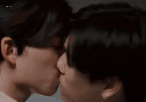 two men are kissing each other on the lips in a close up of their faces .