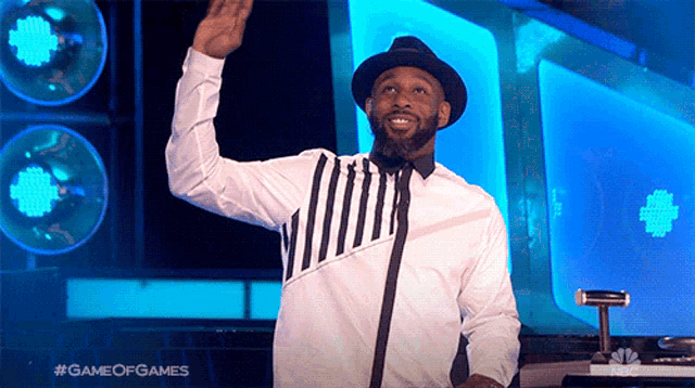 a man in a white shirt and black hat is standing in front of a microphone with the words game of games written on the bottom