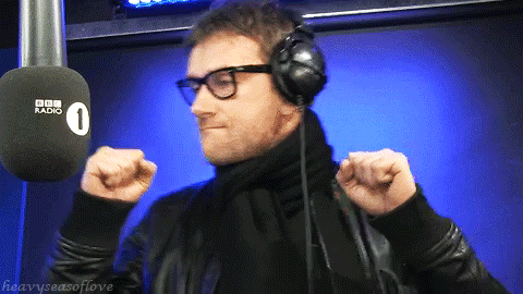 a man wearing headphones and glasses stands in front of a microphone that says bbc radio 1