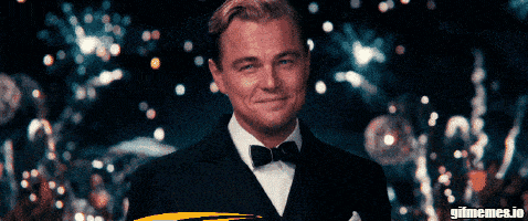 a man in a tuxedo is smiling in front of a gif meme.io banner