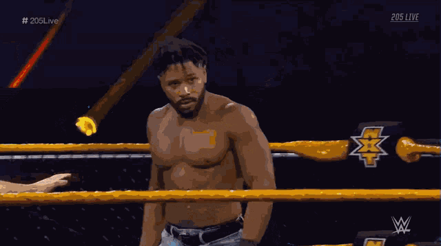 a shirtless wrestler is standing in a wrestling ring with a referee during 205 live