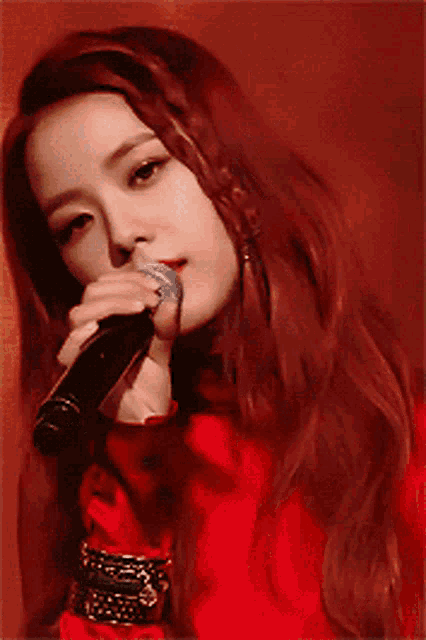 a woman singing into a microphone with red hair