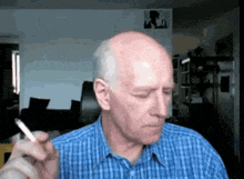 a bald man is smoking a cigarette in a living room