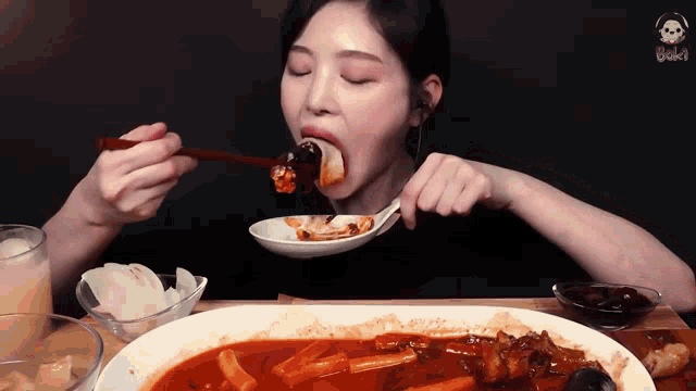 a woman is eating a large plate of food with chopsticks